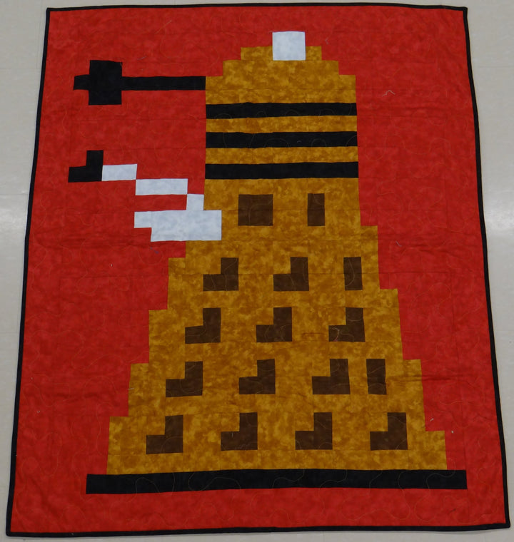 Finished Sci-Fi Evil Robot pixel quilt in gold, brown and black on red, hung flat